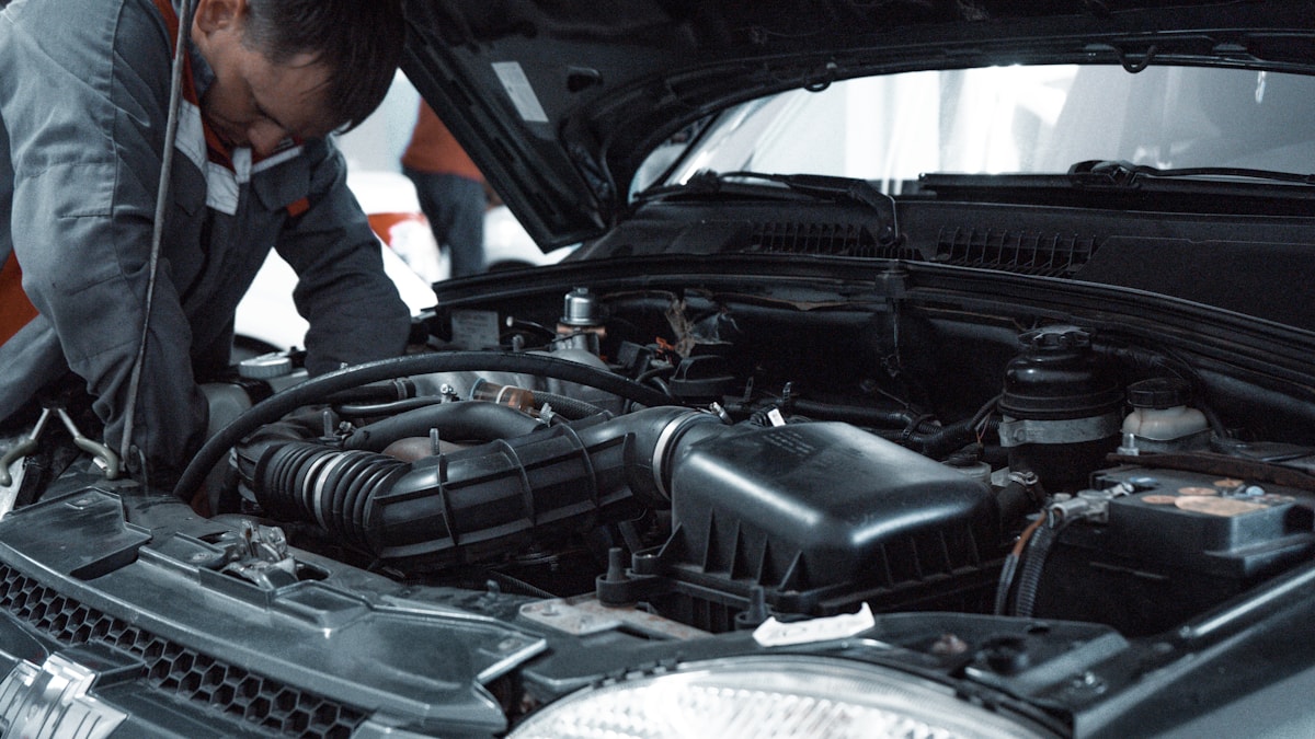 Mechaniker arbeitet am Motorraum — fachgerechte Kfz-Reparatur