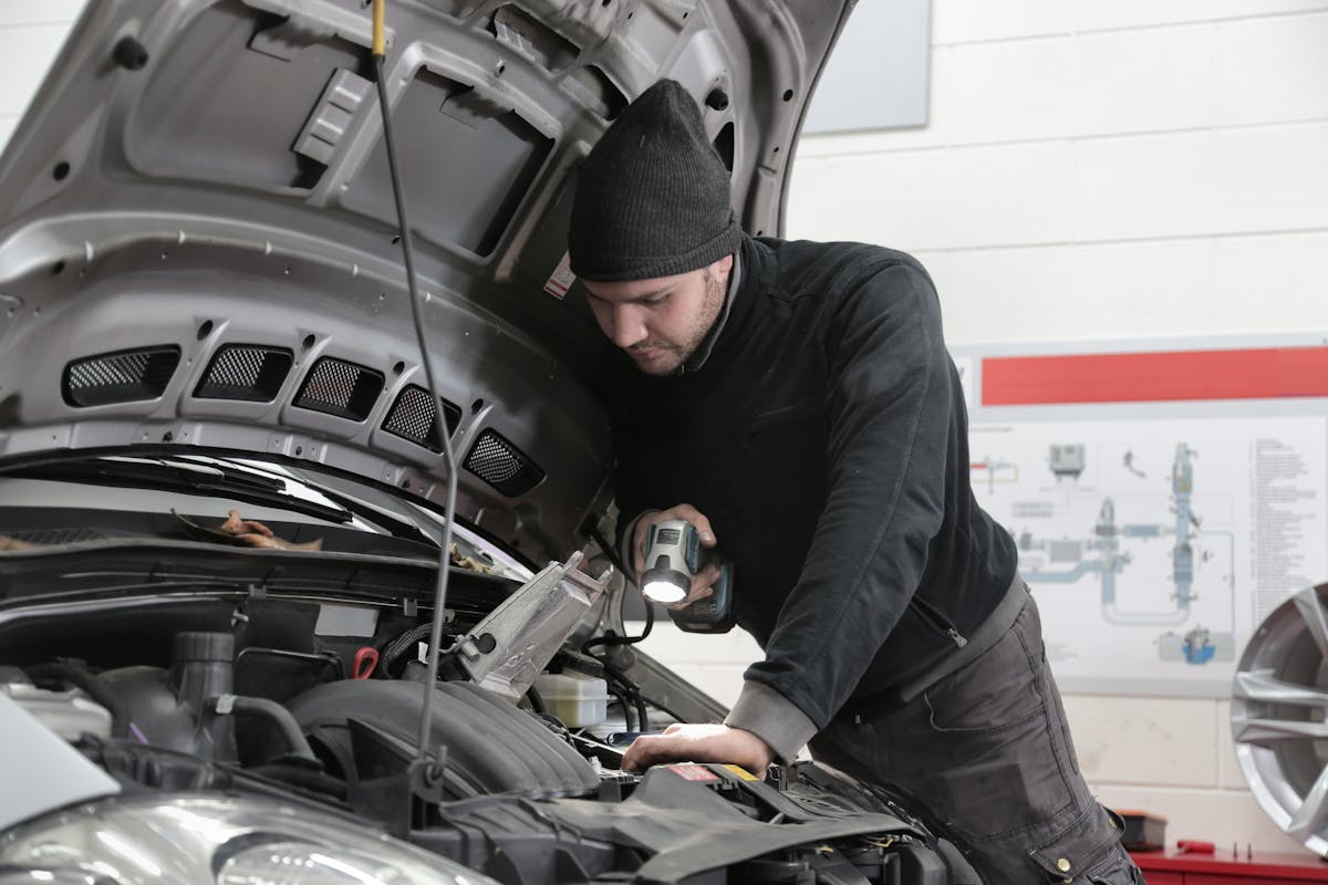Mechaniker prüft Fahrzeugdetails in der Werkstatt — professionelle Kfz-Betreuung